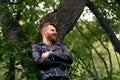 Young man smiling leaning his back against a tree in a forest Royalty Free Stock Photo