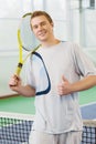 Young man smiling and posing with tennis racket indoor Royalty Free Stock Photo