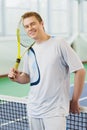 Young man smiling and posing with tennis racket indoor Royalty Free Stock Photo