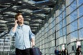 Young man smiling at station with bag and mobile phone Royalty Free Stock Photo