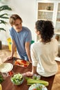 Young man smiling, talking to his girlfriend while preparing healthy meal in the kitchen together. Vegetarianism Royalty Free Stock Photo