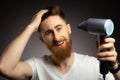 Young man smiling while using hair dryer isolated over black background Royalty Free Stock Photo