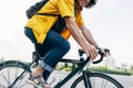 Young man smiling and wearing yellow shirt with backpack and his bike walking in the city street. Male courier with curly hair Royalty Free Stock Photo