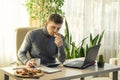 A young man snacks on sandwiches while working at the workplace. The student has a snack