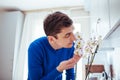 Young man sniffing orchid in kitchen at home