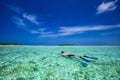 Young man snorkling in tropical lagoon with over water bungalows, Maldives