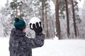 A young man with a snowball in his hand is having fun, swinging for a throw. Winter family and friendly games and entertainment in Royalty Free Stock Photo