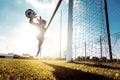 Young man soccer player is training alone for football at the stadium at sunset - Goalkeeper catches the ball Royalty Free Stock Photo