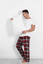 Young man with soft pillow near wall Royalty Free Stock Photo