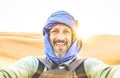 Young man solo traveler taking selfie at Erg Chebbi desert dune