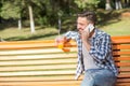 Young man speaking over mobile phone on the bench outdoors Royalty Free Stock Photo