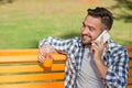 Young man speaking over mobile phone on the bench outdoors Royalty Free Stock Photo