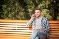 Young man speaking over mobile phone on the bench outdoors Royalty Free Stock Photo