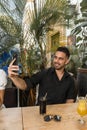 young man spending time in outdoor restaurant having a cocktail and taking selfie Royalty Free Stock Photo