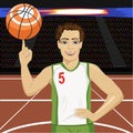 Young man spinning basketball ball with his finger on court in arena