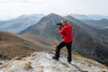A young man sports athlete stands on the mountain and photographs beautiful landscapes Royalty Free Stock Photo