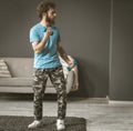 A young man sports in his room. Exercise with dumbbells. The curly-haired guy is holding dumbbells in his hands. Royalty Free Stock Photo