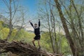 Young man in sportswear and shorts climbing a fallen tree trunk euphoric with arms raised with selective focus Royalty Free Stock Photo