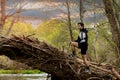 Young man in sportswear and shorts climbing on a fallen tree trunk looking at the horizon with a stream and mountains in the Royalty Free Stock Photo