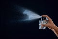 Young man spraying perfume on black background