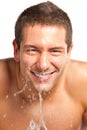 Young man spraying water on his face after shaving in the bathroom Royalty Free Stock Photo