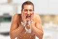Young man spraying water on his face after shaving in the bathroom Royalty Free Stock Photo