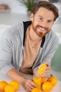 young man squeezing oranges at home