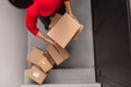 Young man stacking cardboard boxes on doorstep in urban setting. Clean grey steps provide a neutral backdrop. Concept of Royalty Free Stock Photo