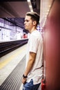 Young man standing against wall in train or subway station Royalty Free Stock Photo