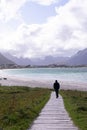 Young man standing at the beach with clouds and blue sky the sea at Ramberg Lofoten Islands, Norway Europe Royalty Free Stock Photo