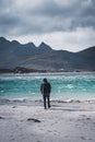 Young man standing at the beach with clouds and blue sky the sea at Ramberg Lofoten Islands, Norway Europe Royalty Free Stock Photo