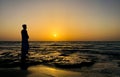 A young man standing at beach in front of sunrise. Sad expression, sad emotion, sadness. Boy sitting alone. Royalty Free Stock Photo