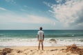 Young man standing on the beach and looking at the sea. Summer vacation concept, Male tourist standing in front of a sandy beach Royalty Free Stock Photo