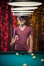 A young man standing in billiard club holding a cue Royalty Free Stock Photo