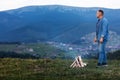 Young man standing by a burning fire under the evening sky in the mountains. Active lifestyle concept Royalty Free Stock Photo