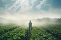 Young man standing in a green field on a foggy day. Back view Royalty Free Stock Photo