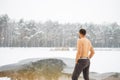 Young man standing by ice hole and ready to swim in the winter water Royalty Free Stock Photo