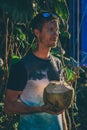 Young man standing in the jungle holding a a fresh coconut drink Royalty Free Stock Photo