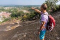 Young man is standing on a mountain and showing something in front