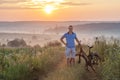 Young man standing near bicycle in morning sunrise with wonderf Royalty Free Stock Photo