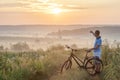 Young man standing near bicycle in morning sunrise with wonderf Royalty Free Stock Photo