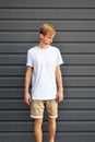 Young man standing near the gray wall in a white T-shirt Royalty Free Stock Photo