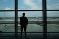 Young man is standing near window at the airport and watching plane before departure. Royalty Free Stock Photo