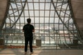 Travel lifestyle :Young man is standing near window at the airport and watching plane before departure. he is standing and carryin Royalty Free Stock Photo