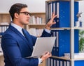 Young man standing next to the shelf with folders Royalty Free Stock Photo