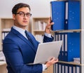 Young man standing next to the shelf with folders Royalty Free Stock Photo