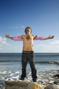 Young Man Standing on Ocean Rock with Arms Outstre Royalty Free Stock Photo