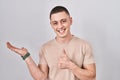 Young man standing over isolated background showing palm hand and doing ok gesture with thumbs up, smiling happy and cheerful Royalty Free Stock Photo