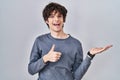 Young man standing over isolated background showing palm hand and doing ok gesture with thumbs up, smiling happy and cheerful Royalty Free Stock Photo