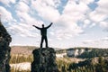 Young man standing with raised hands on top of a mountain and enjoying valley view Royalty Free Stock Photo